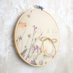 Alianza de boda Silvestre de Novellie en plata, con diseño elaborado y detalles finos, sobre fondo neutro.